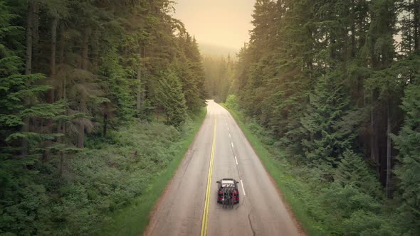 Car With Bicycles Passing On Rural Highway At Sunset alt