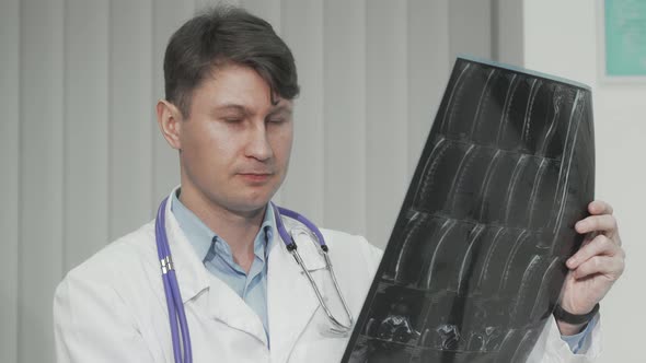 Cheerful Mature Male Doctor Smiling to the Camera While Examining MRI Scan alt