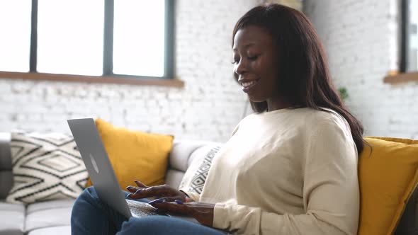 Charming Modern Woman Using Laptop While Sitting on Comfortable Couch at Home