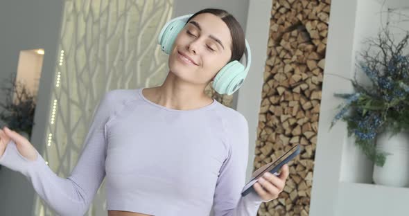 Happy Cheerful Young Woman Dancing Alone at Home and Using Smartphone for Listening Music alt