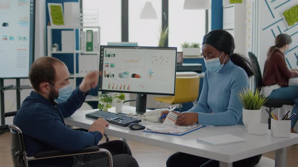 Invalid Man and African Employee with Protective Masks Working Together alt