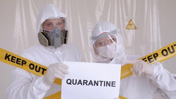 Two Doctors in Protective Suits with Placard QUARANTINE in the Laboratory. Covid alt