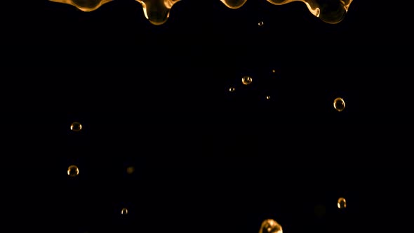 Super Slow Motion Shot of Falling Golden Droplets Isolated on Black Background at 1000 Fps alt