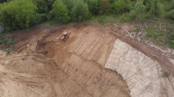 Aerial view of bulldozer flattening surface on further construction site