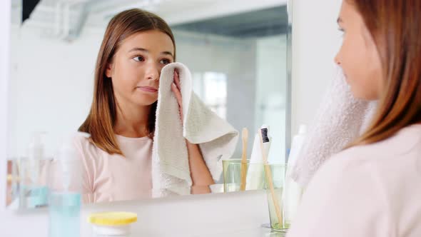 Teenage Girl Wiping Face with Towel at Bathroom alt