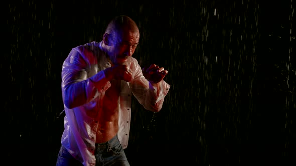 a Man in an Unbuttoned White Shirt is Boxing in Streams of Water on a Dark Background alt
