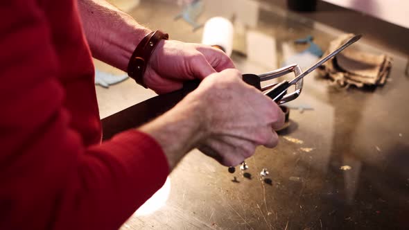 Leather Workshop  a Man Screws a Buckle to a Leather Belt alt