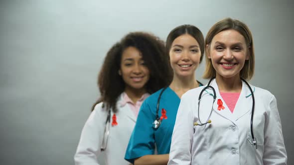 Smiling Multiracial Doctors With Red Ribbons, International AIDS Awareness Sign alt