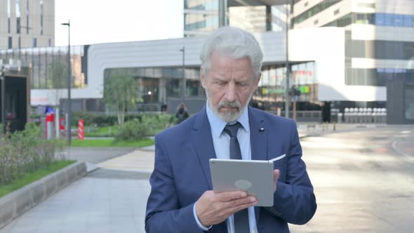 Walking Old Businessman Using Tablet alt