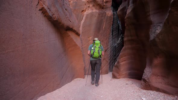 Hiker Hiking On Dry Riverbed In Cave Of Deep Slot Canyon With Orange Curve Rocks alt