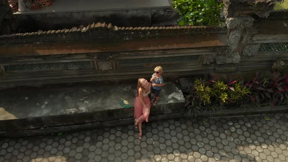 Aerial Shot of the Family Travelers Sitting in a Stairs of the Pura Gunung Lebah Temple in Ubud on alt