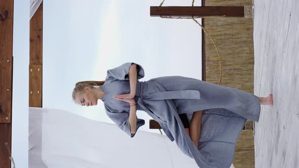 At Terrace Blonde Woman in the Blue Robe Standing in Yoga Pose in Namaste alt