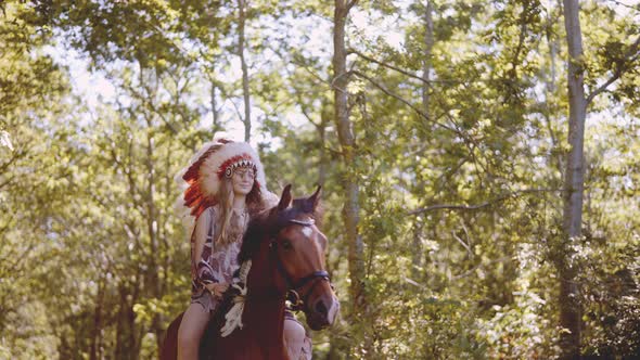 Young Woman In Headdress Riding Horse In Sunlit Forest alt