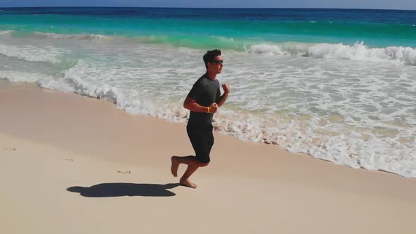 Athletic Man Run Along Ocean Surf By Water