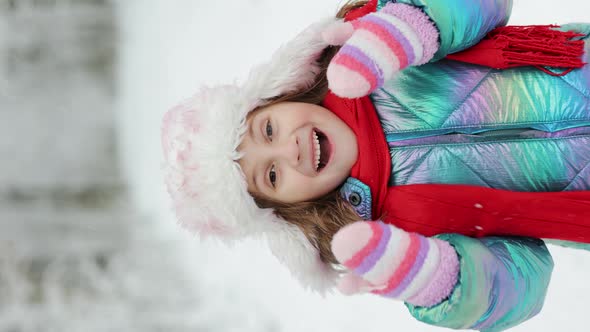 Vertical Video Portrait of Cute Surprised Little Girl in Winter Forest Looks at Camera and Smiles