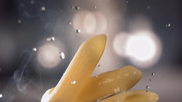 Pasta Penne is Flying Up on a Kitchen Bokeh Background alt
