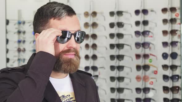 Mature Man Trying on Sunglasses at the Opticians Store alt