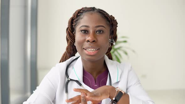 Young African American Woman Doctor Having Chat or Consultation on Laptop Looking Directly to the alt