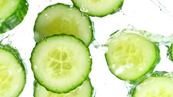 Super Slow Motion Shot of Cucumber Slices Falling Into Water on White Background at 1000Fps alt