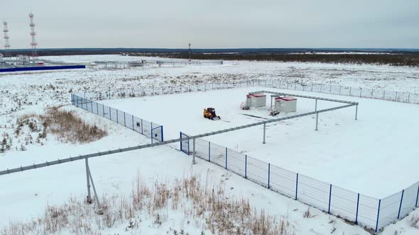 Clearing Snow with a Small Loader in the Taiga on the Oil and Gas Field alt
