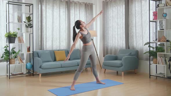 Young Asian Athletic Female In Sports Clothes Stretching And Practicing Yoga At Home alt