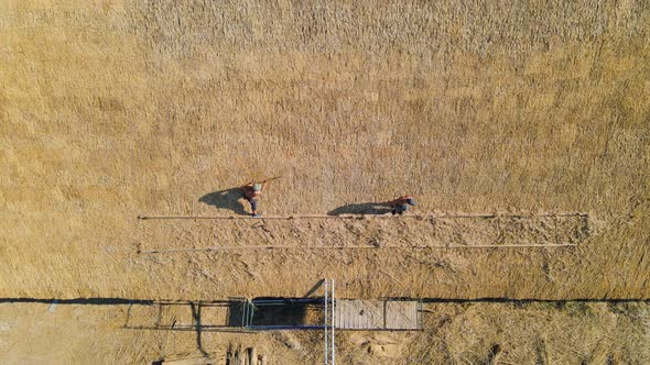 Aerial View the Roof of a Large House with Dry Straw and Hay. Workers Who Install the Roof alt