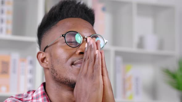 Close up face African man with glasses sitting and taking a rest in working room at home alt