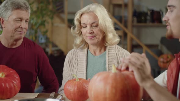 A Man Explains to His Loved Ones How to Draw a Pumpkin for Halloween alt