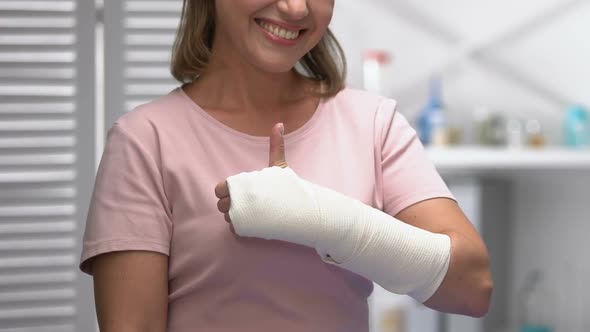 Smiling Woman in Arm Elastic Bandage Showing Thumbs-Up, Doctor Examination