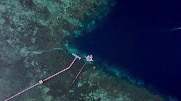 Coral reef island in Raja Ampat Indonesia with boat leaving diving pier area, Aerial top view loweri alt