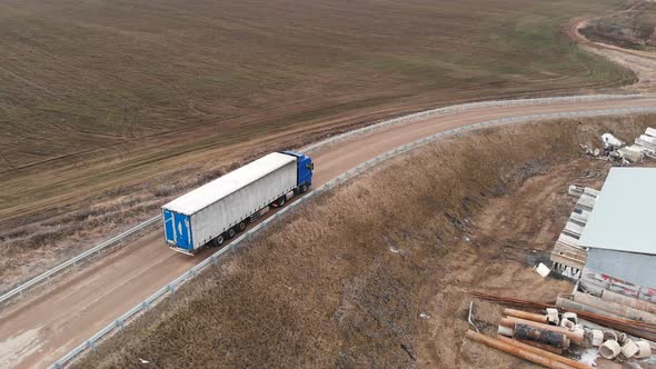 Aerial View of a Large Truck with a Trailer Driving Along a Dirt Road in Search of a Place for a U alt