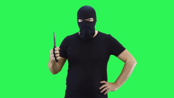A man in a black mask holds a knife in his hand.Balaclava.Green screen background