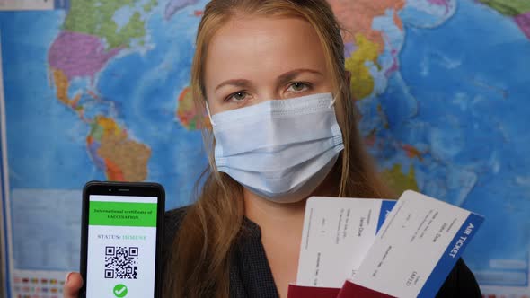 Woman in a Mask Holds a Phone with a Certificate of Vaccination Against Covid19 alt