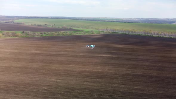 Aerial scenic of a tractor spraying on land field