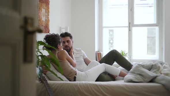 Young American Couple is Talking and Hugging While Lying on Bed in White Bedroom Spbd alt
