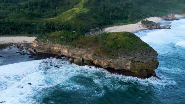 Majestic rock hit by ocean wave on Kasap beach, Java, Indonesia aerial view alt