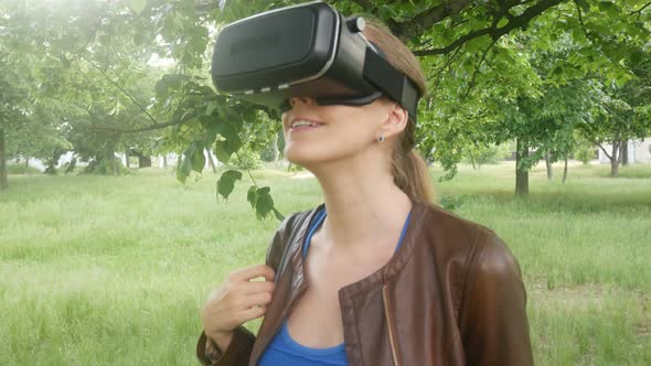 Cheerful Woman Uses A Modern Helmet Of Virtual Reality In The Park