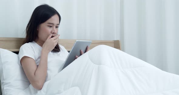 Young woman used tablet before sleeping on bed