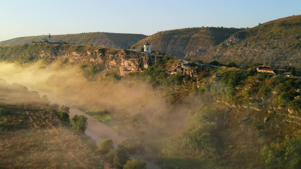 Aerial drone view of the Old Orhei at sunset. Valley with river and fog, monastery located on a hill alt