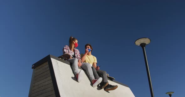 Happy caucasian woman and man friend wearing face mask, sitting and laughing alt