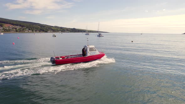 A Small Passenger Ferry at Sea Motoring Alongside an Island alt