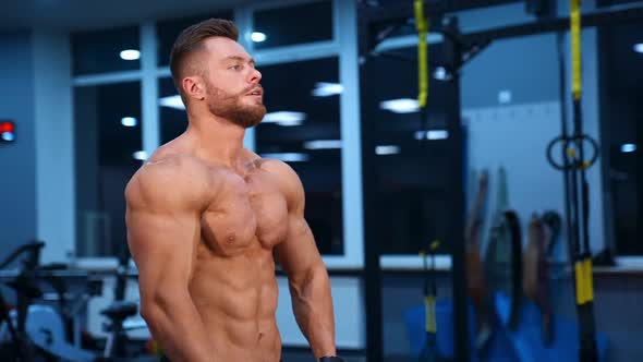 Model bodybuilder poses to the camera and shows perfect abs and strong body. Slow motion. alt