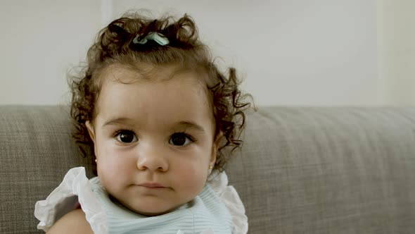 Closeup of Cute Toddler Sitting on Sofa Looking at Camera alt
