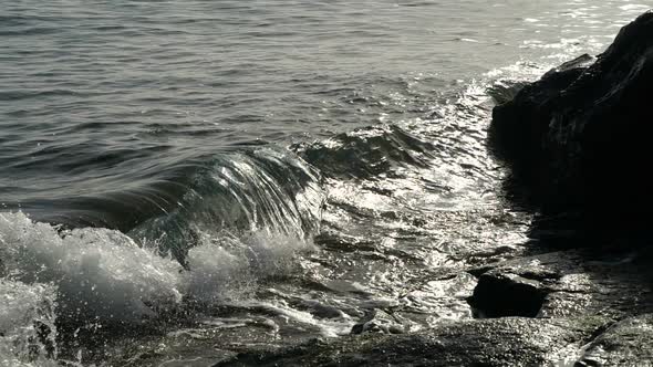 Ocean Wave Rises in the Air at Beautiful Sunset Light. Slow Motion. Big Wave Is Crashing on Rocks alt