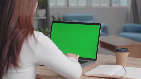 Girl Typing On Computer Keyboard Of A Laptop Computer With Green Screen Display At Home alt