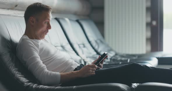 Man Sits on Sofa Uses Tablet and Rejoices at the Received Good News alt
