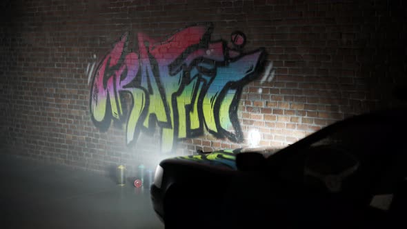 Police car lights illuminating old brick wall with fresh graffiti tag on it.4KHD alt