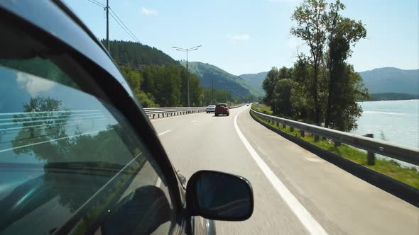 Car is moving along the Katun river on a highway in Altay, Russia