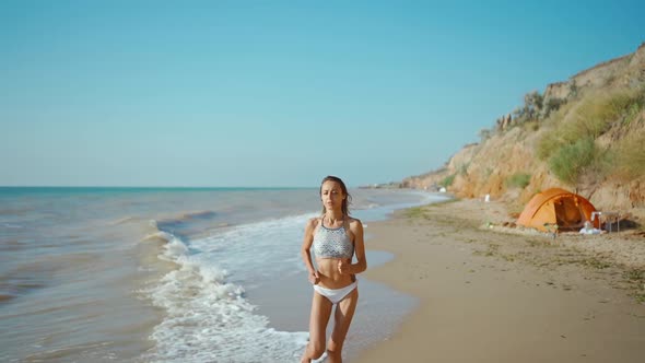 Young Stunning Woman in Bikini with Beautiful Slim Body is Engaged in Gymnastics at Sea at Sunrise alt