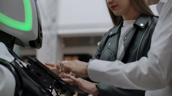 The Couple Communicates with Robot Assistant with Information Screen in Duty to Give Information alt